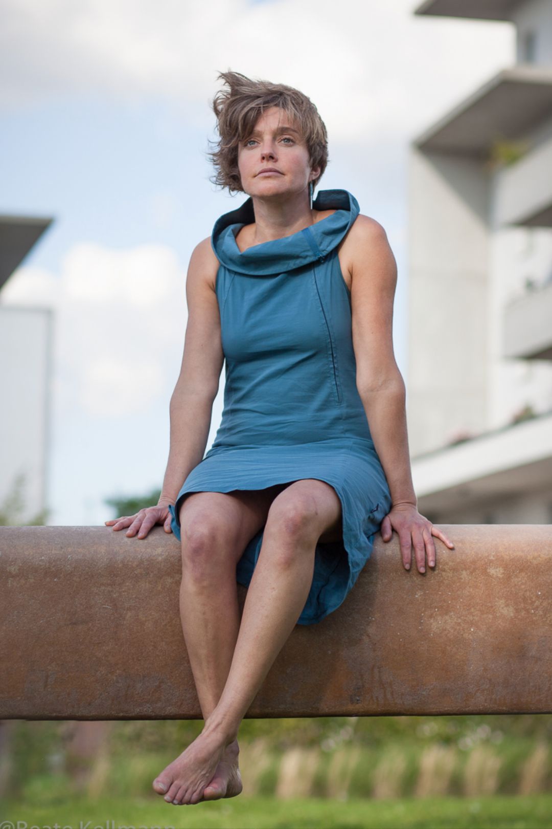 K&uuml;nstler Portrait in M&uuml;nchen mit einer Artistin und T&auml;nzerin. Im M&uuml;nchner westend. Sie sitzt in einem blauen Kleid auf einem Balken. Schauspielerfotoshooting M&uuml;nchen