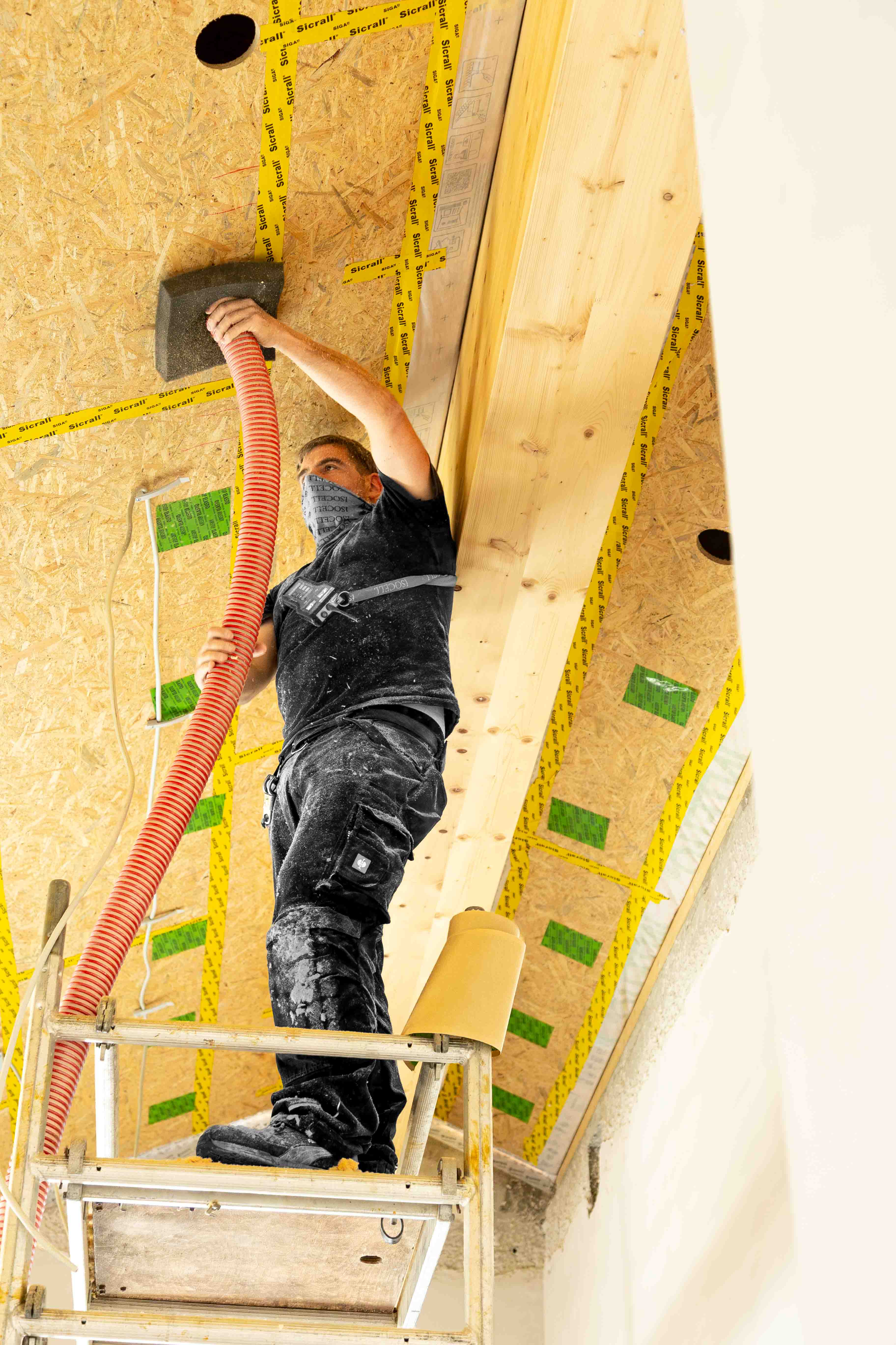 Einblasd&auml;mmung. Mitarbeiter auf dem Ger&uuml;st beim Einblasen des D&auml;mmmaterials.