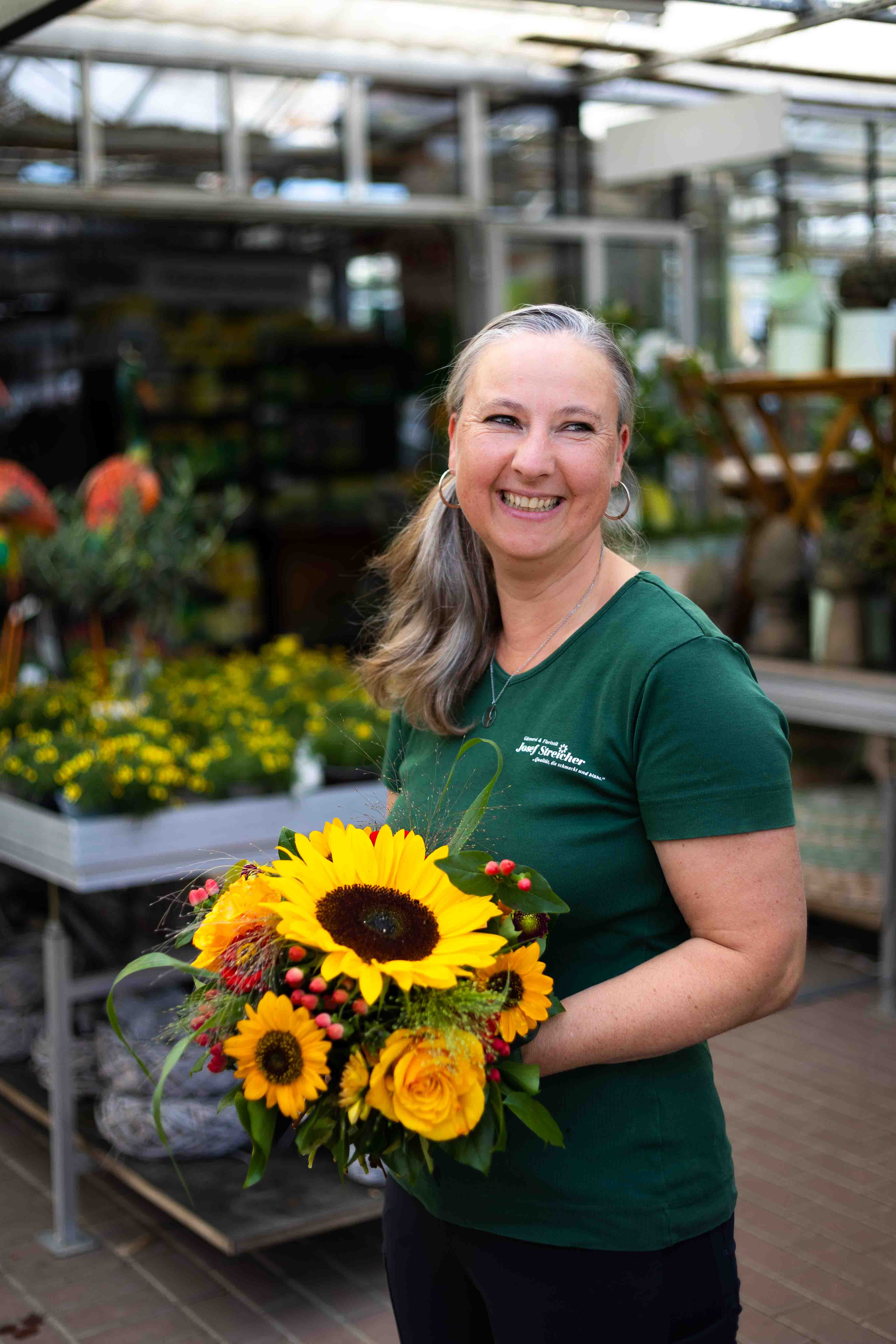 Unterneehmensreportage am Ammersee. G&auml;rtnerin mit Sonnenblumen im Arm.