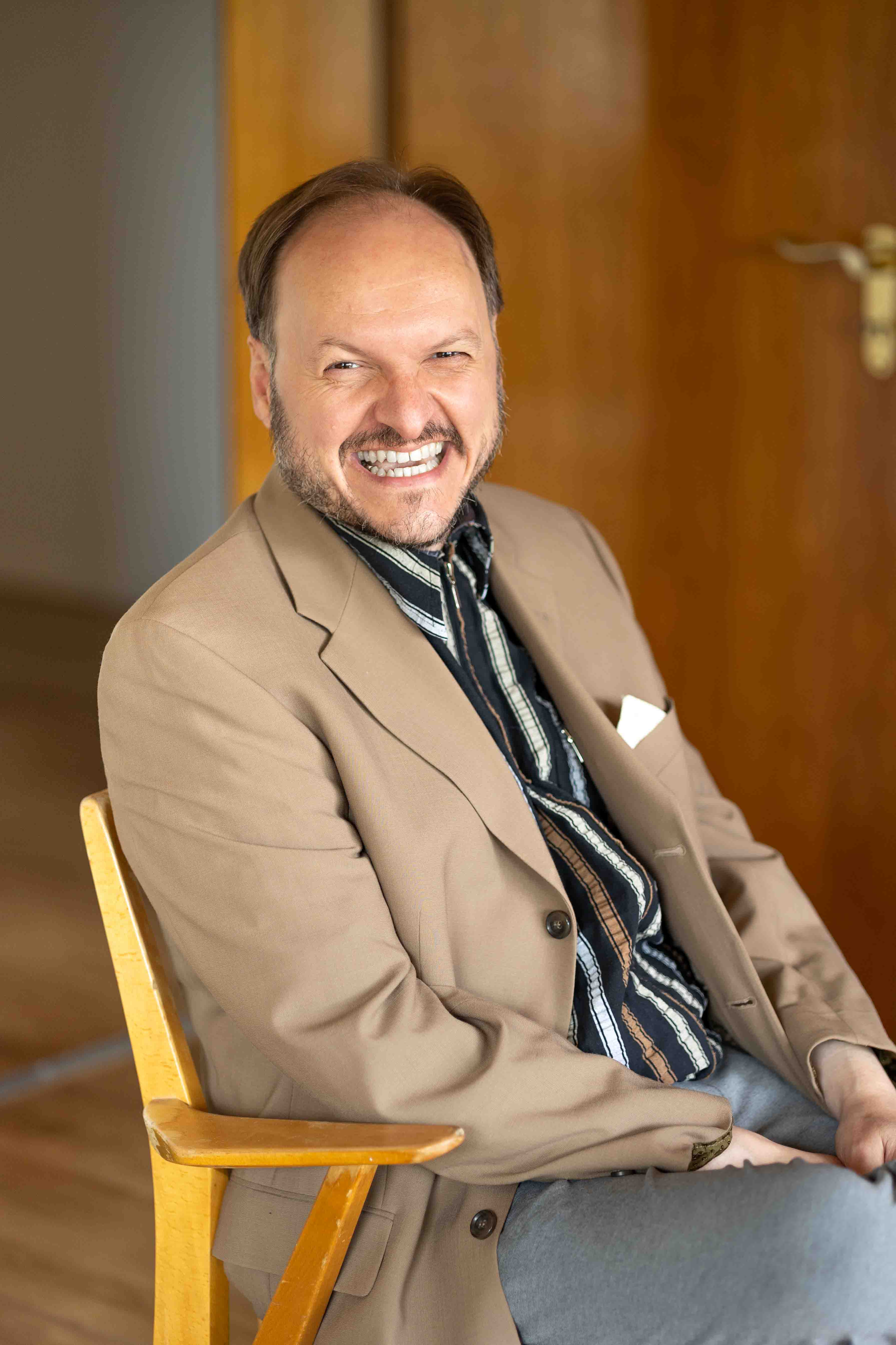 Schauspieler mike sobotka lachend auf einem Stuhl sitzend