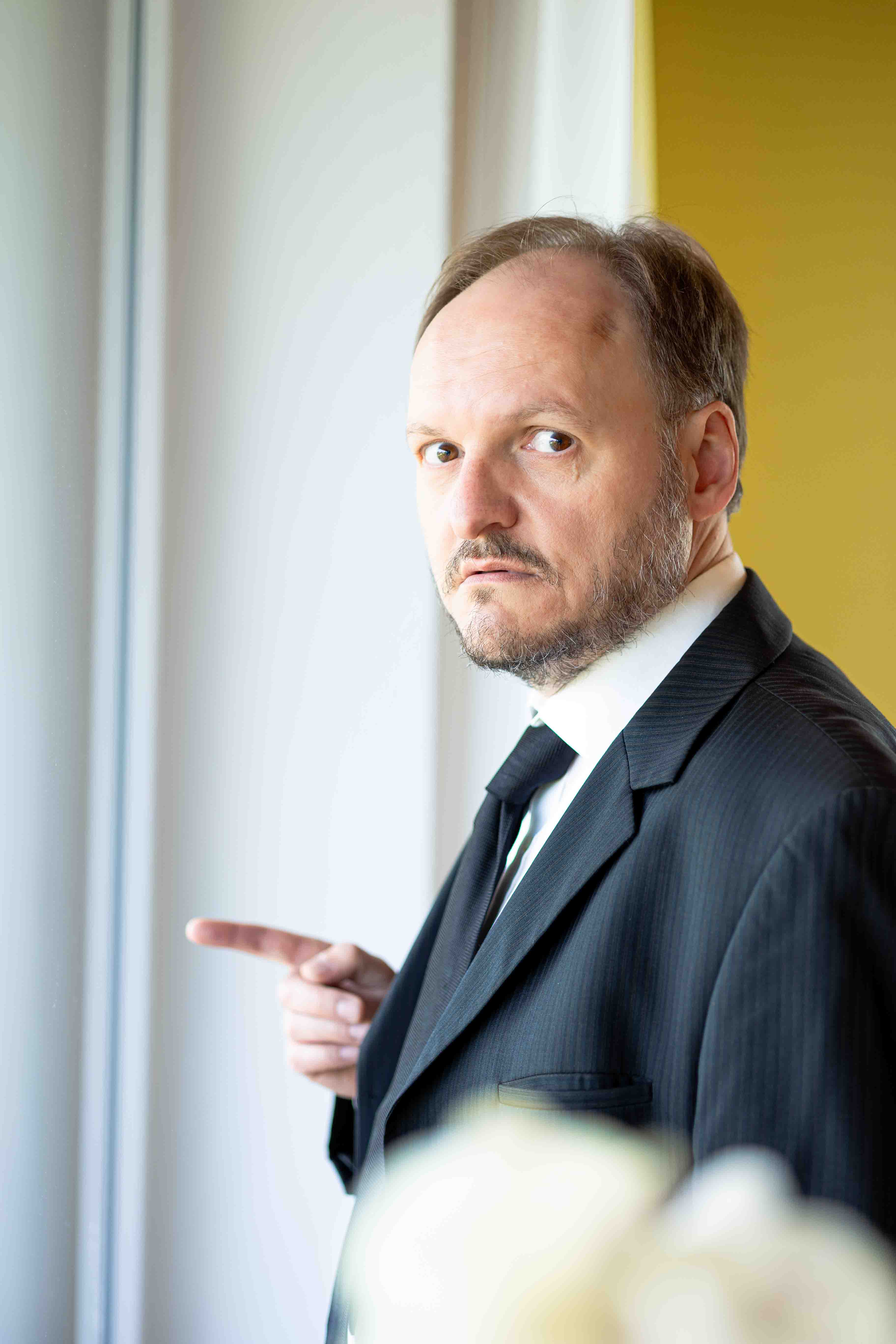 Schauspieler Mike Sobotka am Fenster mit goldenem Hintergrund