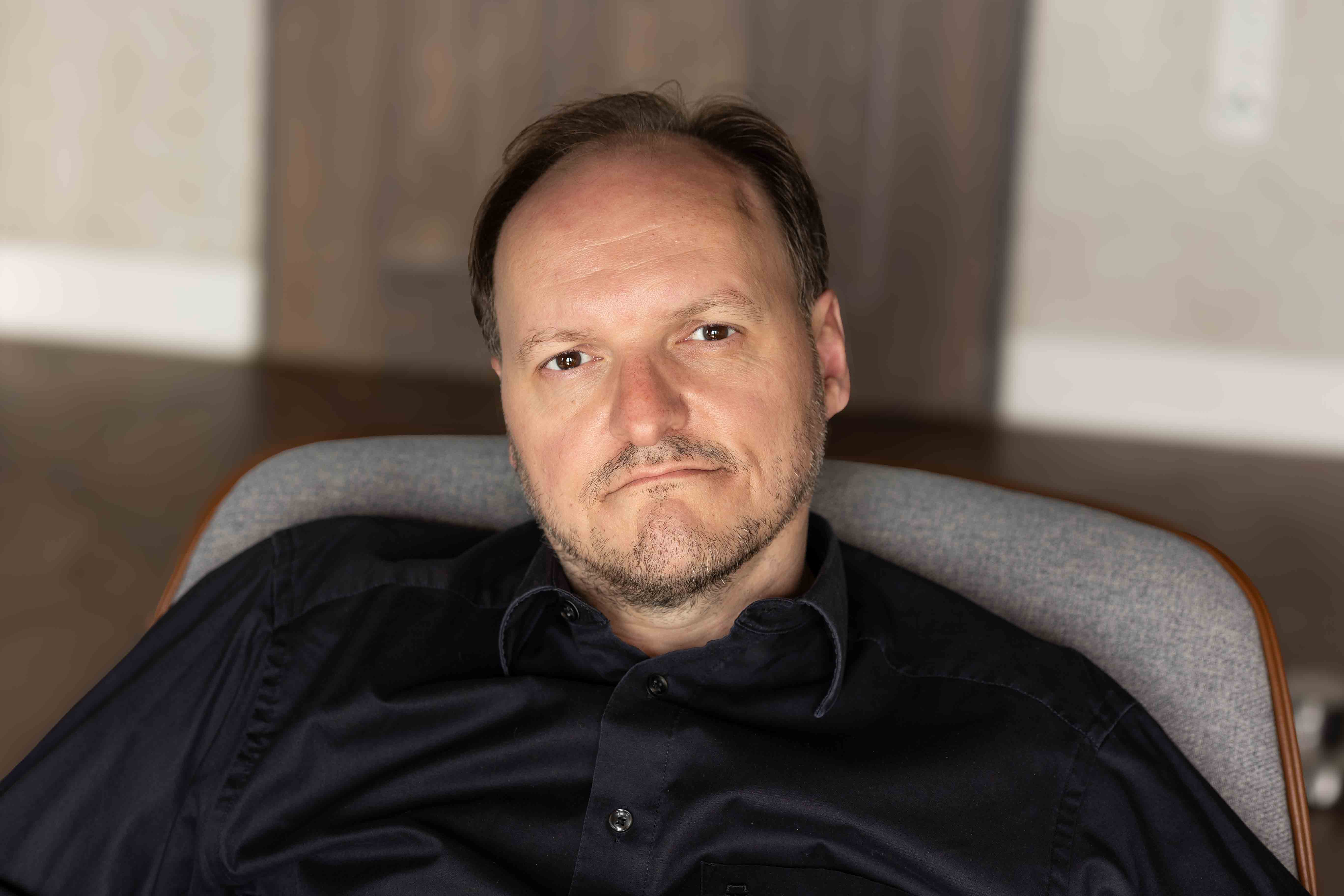 Schauspieler Mike Sobotka mit schwarzem Hemd, Portrait.